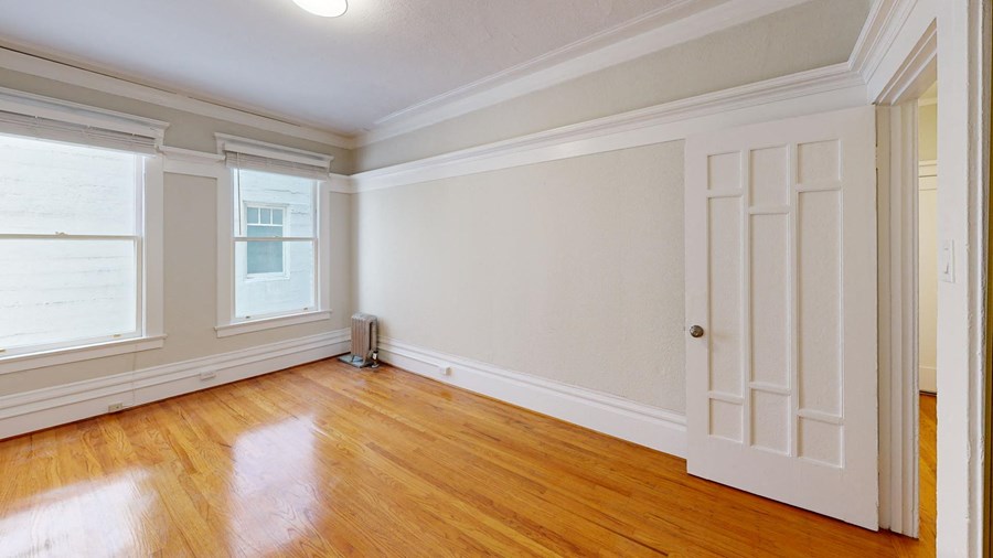 an empty living room with white walls and wood floors